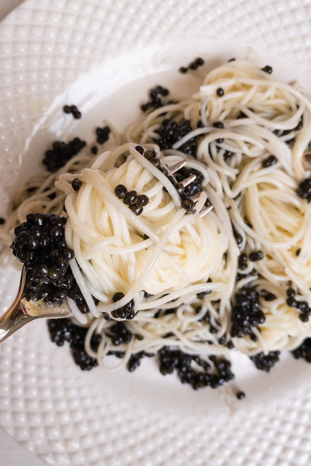 a white plate topped with spaghetti and black caviar