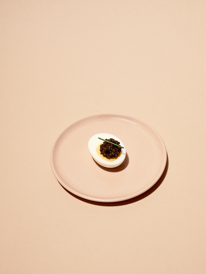 a pink plate with a hard boiled egg and caviar on it