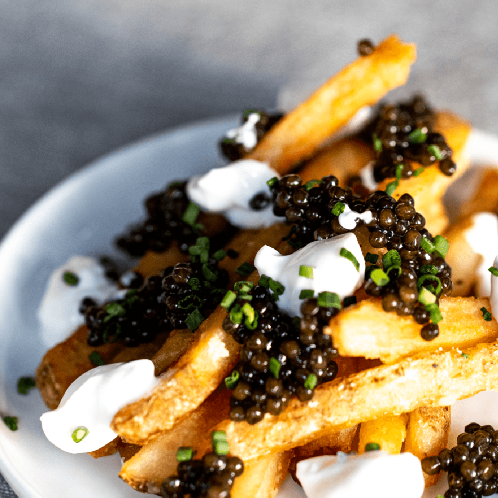 a plate of french fries with caviar and sour cream