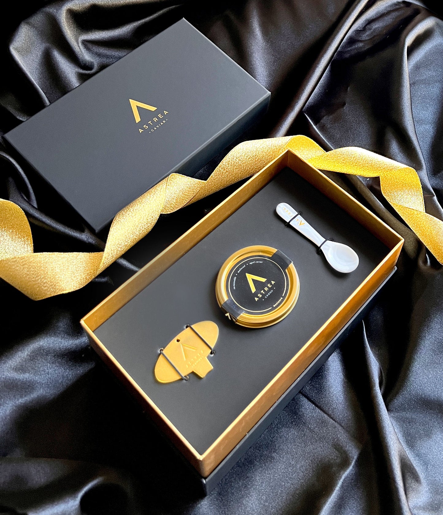 a black box with a jar of astrea caviar in it and a serving spoon