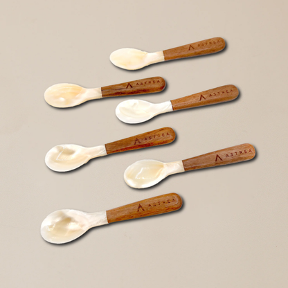 six spoons with astrea written on the handles on a beige surface